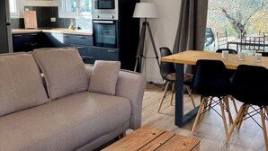 A modern living room with a sofa, a wooden coffee table, and a dining area with a table and chairs. - The Montchamp villa (Chambonas)