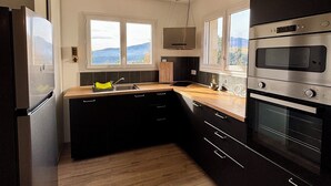 A modern kitchen with black cabinets, stainless steel appliances, and wooden flooring. - The Montchamp villa (Chambonas)