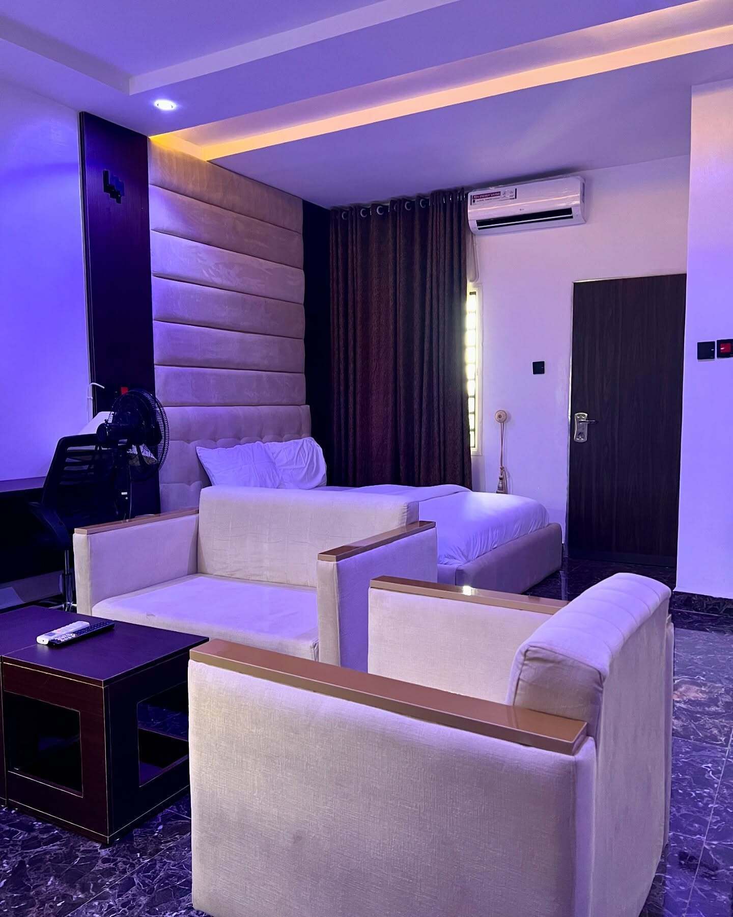 A hotel room with a sofa, armchairs, a coffee table, and a TV.