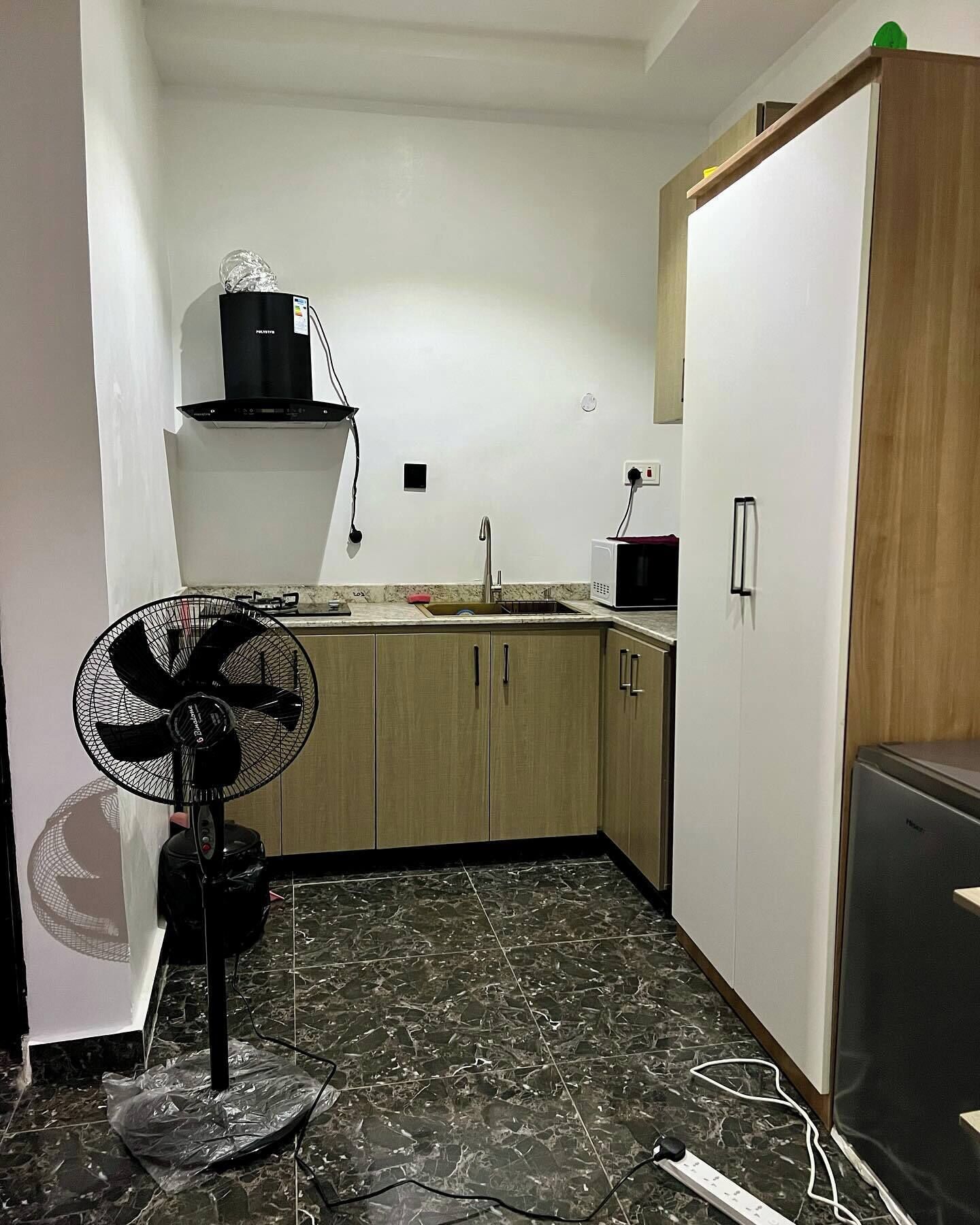 A compact kitchen with a sink, microwave, and a fan.