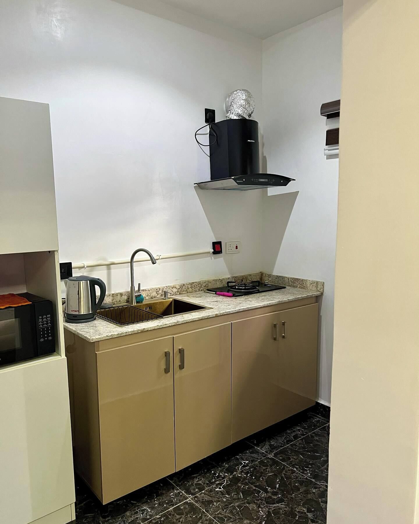 Cocina compacta con microondas, hervidor, pileta y campana extractora.