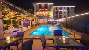 An outdoor pool area with lounge seating and a building labeled "CLASS SUITES" in the background. - Class Suites Hotel and Apartment (Abuja)