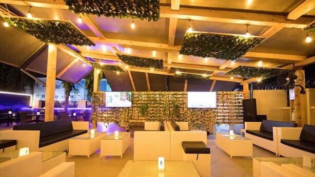 A modern lounge area with white sofas, a coffee table, and a TV screen on the wall. - Class Suites Hotel and Apartment (Abuja)