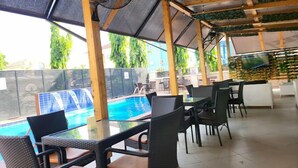 An outdoor dining area with tables and chairs, a pool, and a view of the surrounding area. - Class Suites Hotel and Apartment (Abuja)