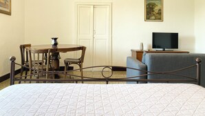 Une chambre d’hôtel comprenant un lit, une télévision, une table à manger avec des chaises et une porte.