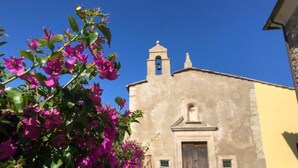 Un bâtiment doté d’un clocher et d’une porte, entouré de bougainvilliers.