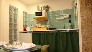 A kitchen with a microwave, a small refrigerator, and a green curtain. - Perfect for exploring Naples without having to use transportation.  (Napoli)