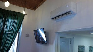 A room with a mounted flat-screen TV, an air conditioning unit, a wooden ceiling, and a door. - Perfect for exploring Naples without having to use transportation.  (Napoli)