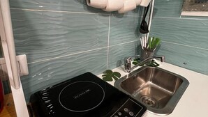 A kitchen with a built-in induction cooktop, a stainless steel sink, and a backsplash with teal tiles. - Perfect for exploring Naples without having to use transportation.  (Napoli)