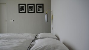 A hotel room with two beds, a wall-mounted light fixture, and three framed pictures. - Dreamlike stone house by the sea: luxury with infinity pool and panoramic views (Herceg Novi)