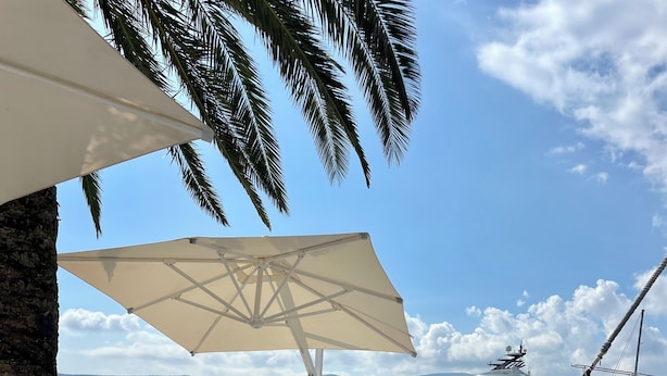 A seaside dining area with tables set for a meal, overlooking the ocean and yachts. - Dreamlike stone house by the sea: luxury with infinity pool and panoramic views (Herceg Novi)