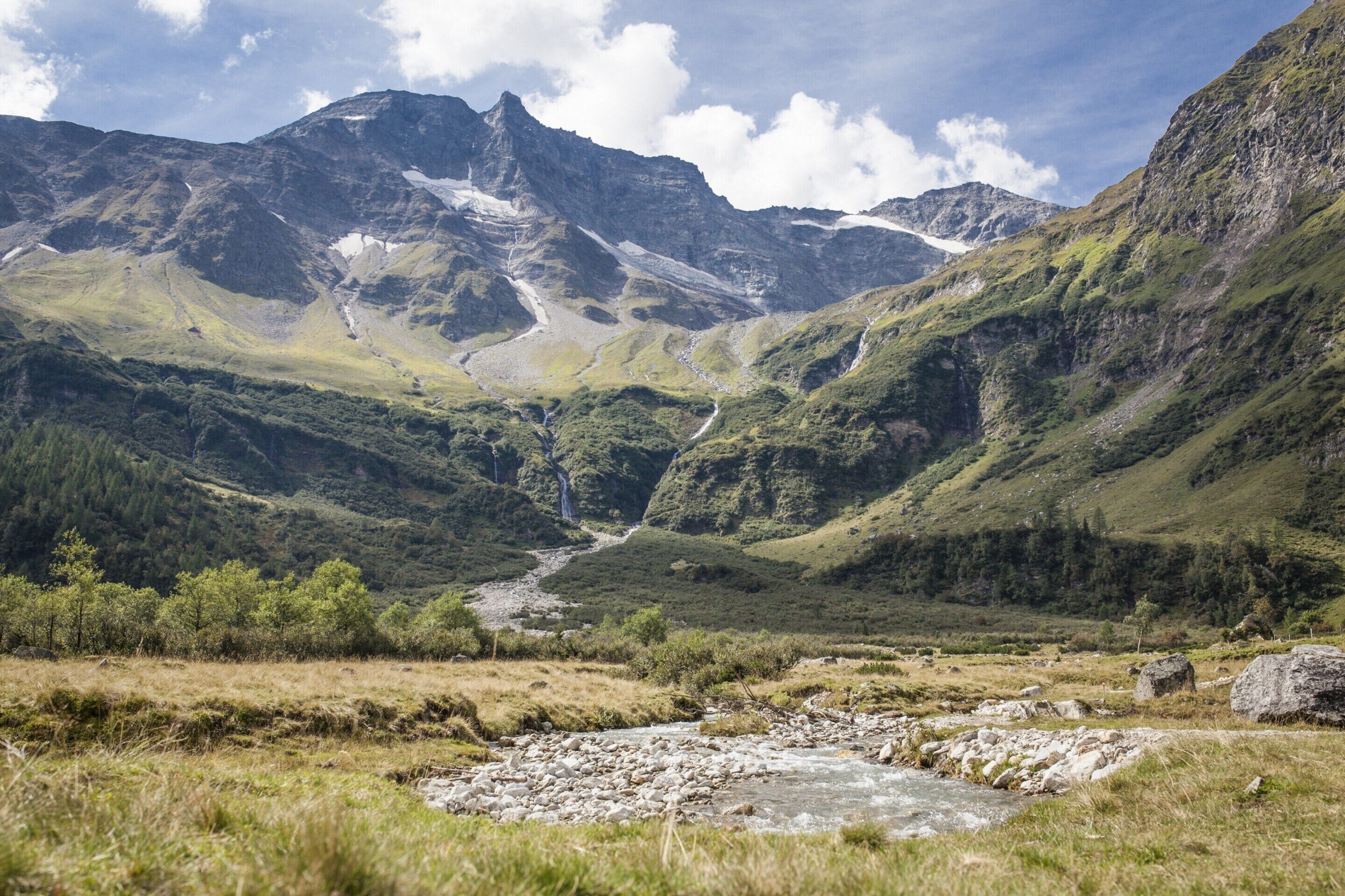Un paisaje montañoso con un río, terreno rocoso y una cascada.