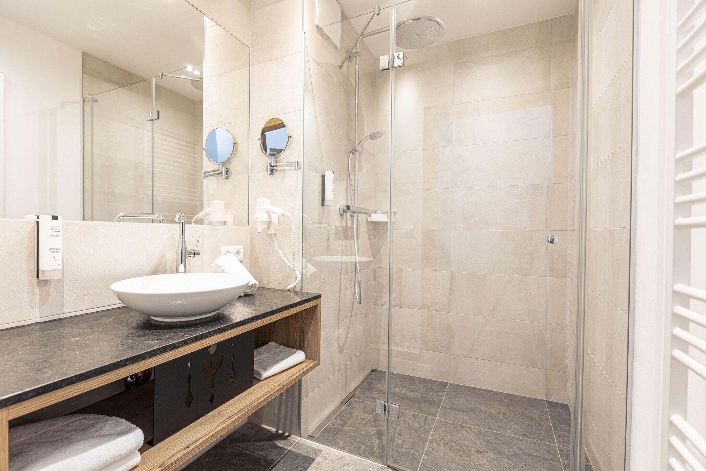 Un bagno moderno con uno specchio grande, un lavandino e una cabina doccia in vetro.
