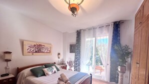A bedroom with a bed, a nightstand, a lamp, a painting, a window with curtains, and a view of the outside. - Comfortable house 100m from the wild beaches of Peniscola Sud. Pets allowed (VC)