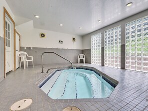 A swimming pool with a tiled deck, a no-smoking sign, and a window with a view of greenery.