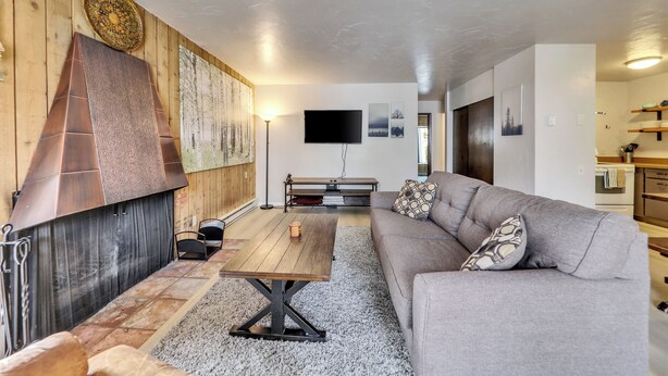 Una sala de estar con chimenea, un sofá, una mesa de centro y un televisor montado en la pared.