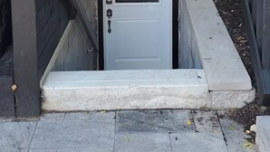 A residential entryway with a brick wall, a small window, and a door with a metal grill. - Stylish 1 Bedroom Apartment close to Bloor West Village (Toronto)