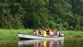 A boat with passengers on a calm river surrounded by dense greenery.