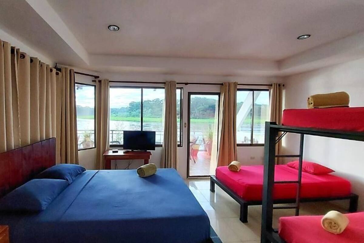A hotel room with a large bed, a bunk bed, a TV, and a view of a lake.