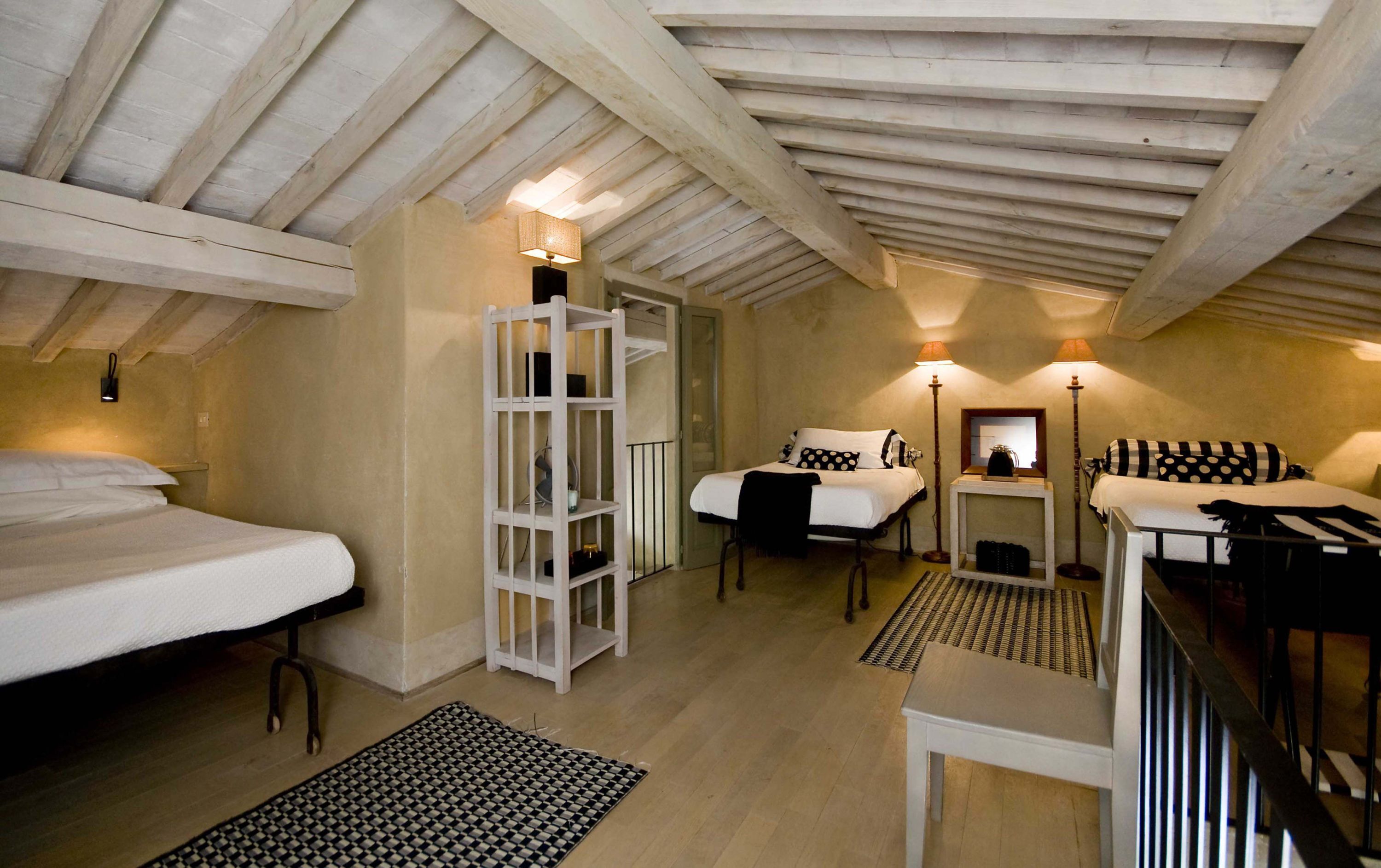 Un dormitorio acogedor en el ático con dos camas, una mesita y una estantería.