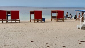 A beach with wooden chairs and a lifeguard stand. - Blue Turquoise Sea Villa (Montego Bay)