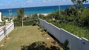 A view of a coastal area with a clear sky, a grassy area, and a white building in the foreground. - Blue Turquoise Sea Villa (Montego Bay)