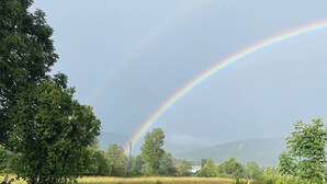 A grassy field with a rainbow, trees, and a distant mountain range. - Beautiful new studio with amazing views - peaceful but close to everything! (Weston)
