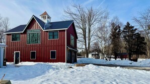 A two-story red barn with a gabled roof and a small tower. - Beautiful new studio with amazing views - peaceful but close to everything! (Weston)