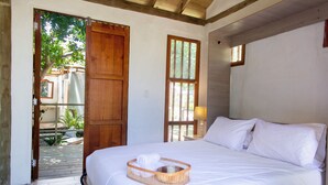 A bedroom with a large bed, wooden door, and a window. - Tiny Village Cartagena Boutique Resort  (Cartagena)