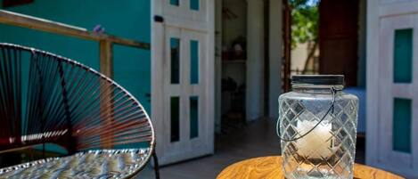 A wicker chair and a wooden table with a glass jar on it.