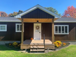 A wooden house with a porch, a door with a wreath, and a mailbox. - Charming 2-bedroom home in quaint Newfield with WiFi (Newfield)
