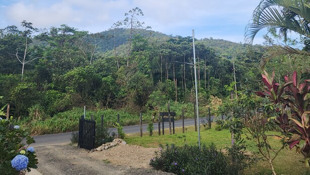A rural landscape with a dirt road, a wooden fence, and a metal pole. - Cabinas El Pilon Rio Celeste (Katira)