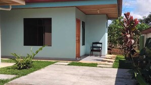 A single-story building with a red roof, a large window, and a small porch area. - Cabinas El Pilon Rio Celeste (Katira)