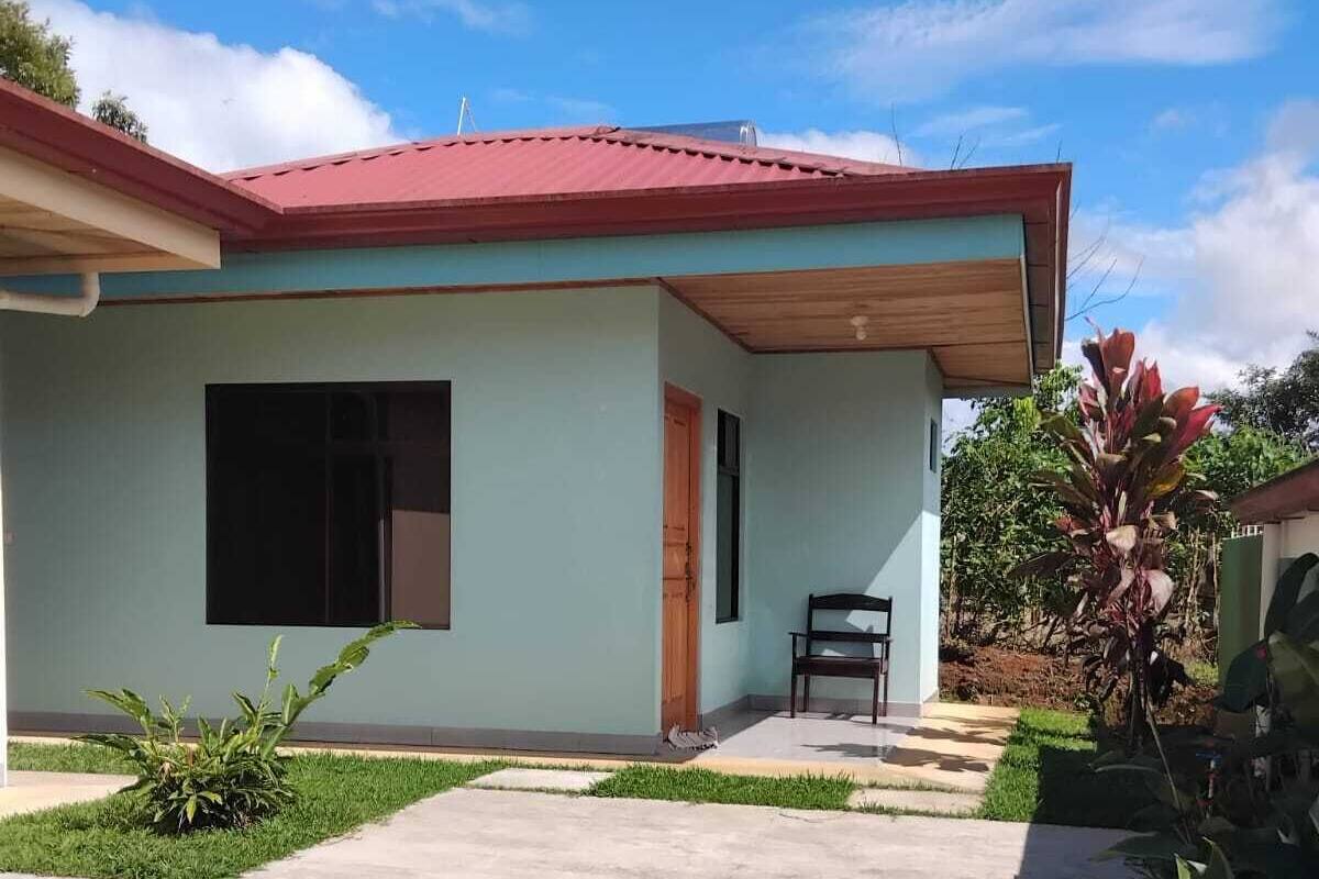 Un edificio de una planta con tejado rojo, un ventanal grande y un pequeño porche.