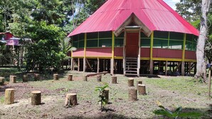 A red-roofed building surrounded by trees and wooden stumps.