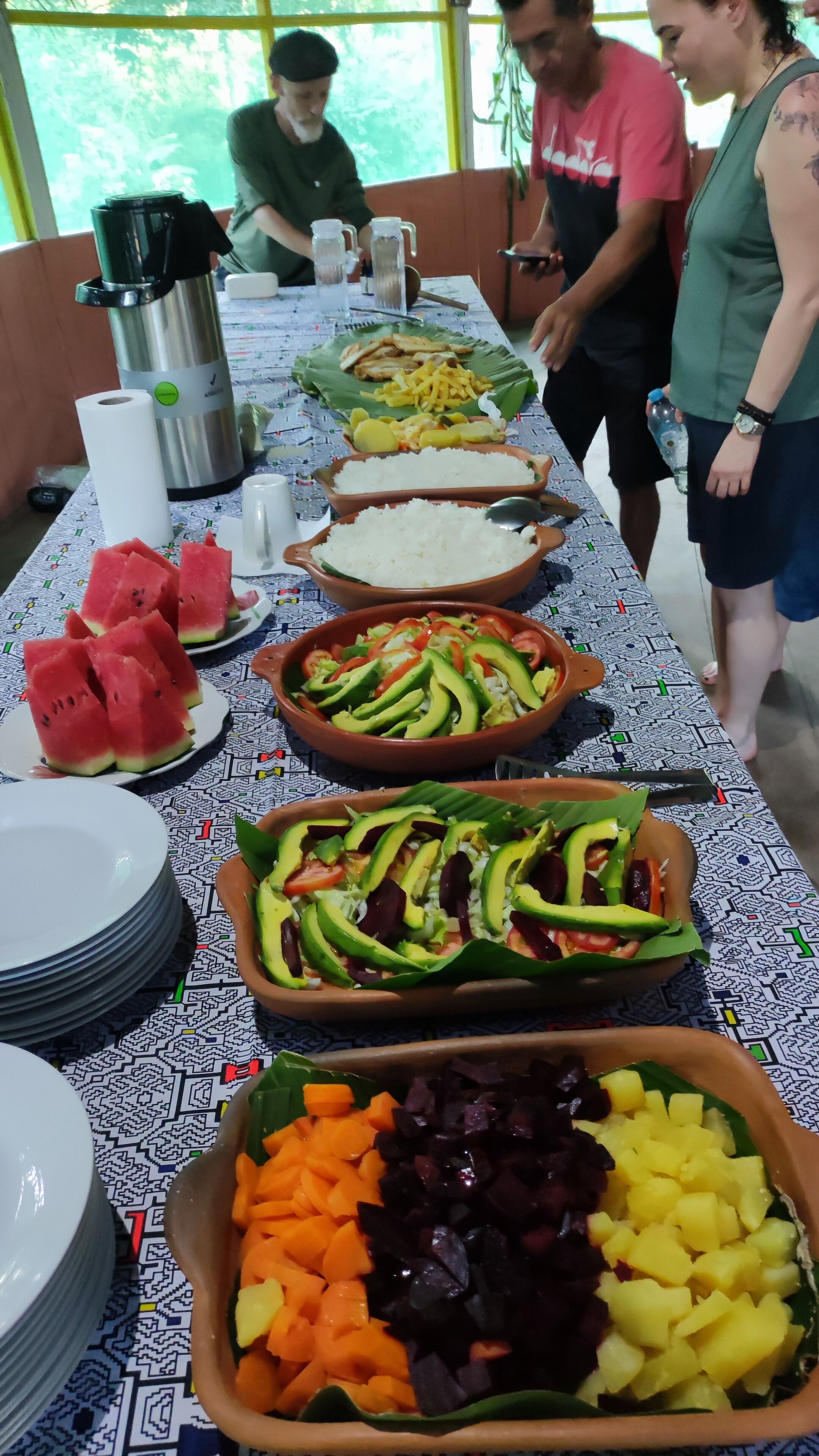 Un tavolo da buffet con diversi piatti, tra cui riso, frutta e verdura.