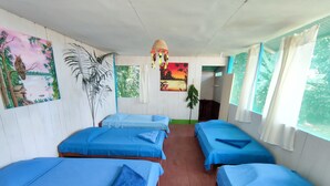 A room with four beds, each covered with blue sheets, and a large painting on the wall.