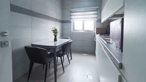 Cozinha moderna com área de refeições, com uma janela com persianas, fogão embutido e uma pequena planta na mesa.