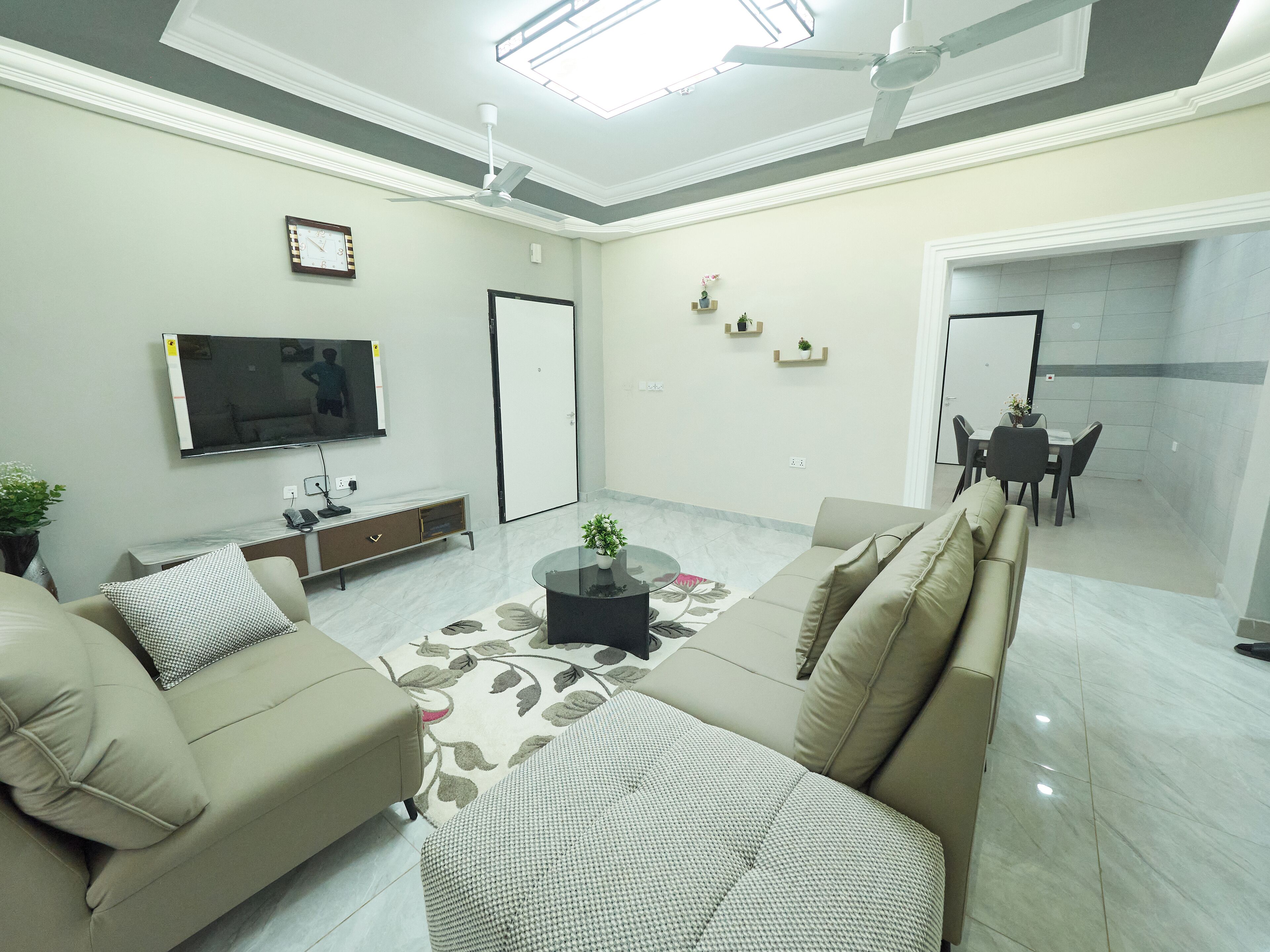 A modern living room with a sofa set, a coffee table, a TV, and a dining area with chairs and a table.
