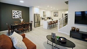 Un appartement moderne comprenant un coin repas, une cuisine, un salon et un escalier.