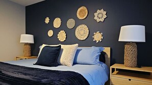 Une chambre à coucher comprenant un lit, deux tables de chevet, une lampe de chevet et des éléments de décoration murale.