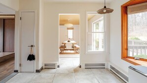 Un hall d’entrée spacieux avec un plancher en bois, un coin repas à l’arrière-plan et une grande fenêtre sur la droite.