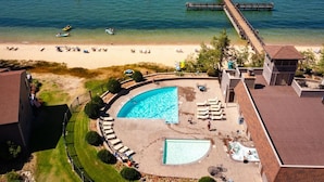 Ein Resort mit großem Schwimmbad, Zugang zum Strand und einer Pier, die sich ins Wasser erstreckt.
