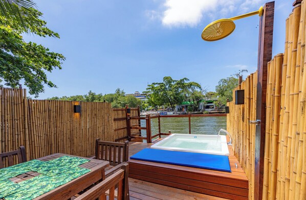 A wooden deck with a hot tub, bamboo fence, and a table with a green tablecloth.