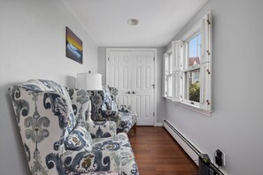 A hallway with a white door, patterned armchairs, a lamp, and a window with shutters. - Waverly Suite 2 (New Shoreham)
