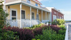 A two-story house with a porch, a brick exterior, and a white fence. - Waverly Suite 2 (New Shoreham)