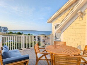 A deck with a table and chairs, overlooking a body of water.