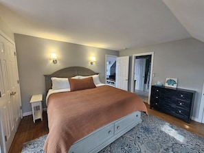 A bedroom with a bed, bedside tables, a dresser, and a door. - Waverly Suite 3 (New Shoreham)