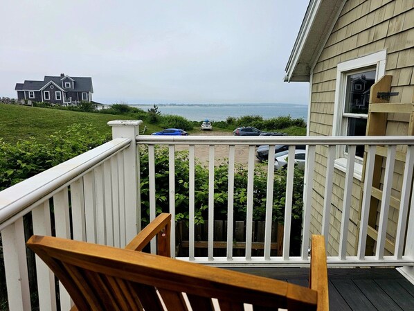 Ein Balkon mit Meerblick, ein Holzstuhl und ein weißes Geländer.