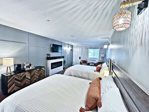 Una habitación de hotel con dos camas, un escritorio con lámpara, televisión y chimenea.